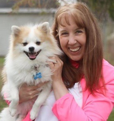 Ronnell Kay Gibson smiling outdoors while holding one of her fluffy Pomeranian pups